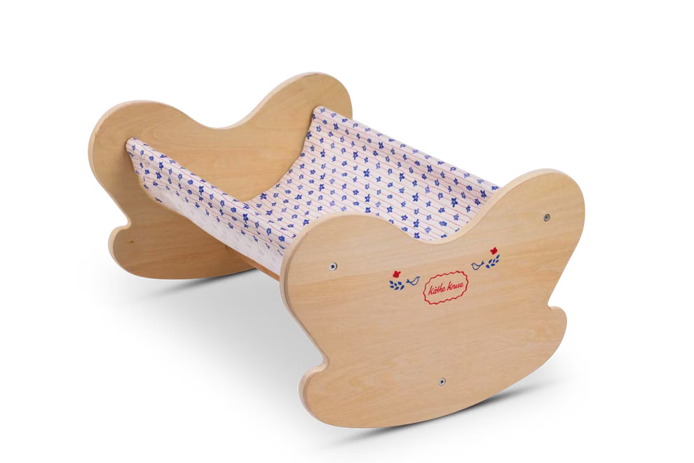 Käthe Kruse Waldorf Puppenwiege Holz_33045 Die Käthe Kruse Waldorf Puppenwiege Holz ist eine kleine hölzerne Puppenwiege mit geschwungenen Enden einer blau gemusterten Stoffschlinge seitlichen Motiven aus roten und blauen Herzen und dem Schriftzug "Herzchen".