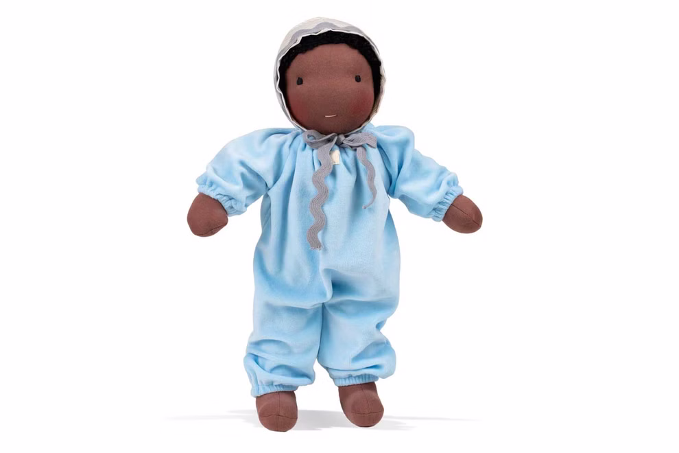 Waldorfkind Baby Puppe nach Waldorfart 46 cm_33709 Die Waldorfkind Baby Puppe nach Waldorfart 46 cm hat mittelbraunes Fell trägt einen hellblauen Overall und eine weiße Mütze mit grauer Schleife und ist vor einem weißen Hintergrund abgebildet.