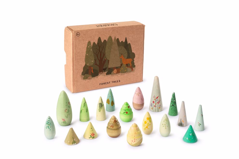 Grapat Bäume Achtzehn handbemalte Holzfiguren in verschiedenen Grün- und Brauntönen, die unterschiedliche abstrakte Baumformen und Zapfen für eine kleine Waldlandschaft darstellen, vor der Verpackung.