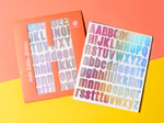 Buchstabensticker in Flieder mit holografischem Effekt auf einem Stickerbogen von Ava & Yves