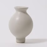 Die Grimm's Grimms Stecker Vase ist eine kleine runde weiße Keramikvase mit schmalem Hals und Fuß die sich vor einem schlichten weißen Hintergrund präsentiert.