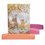 Ein Dekor "Kartenständer Rottöne 3er Set" zeigt eine Postkarte mit einer Herbstszene - eine Frau mit einem Baby und einem Kind unter einem Baum - in einem Holzständer mit orange- rosa- und violettfarbenen Tönen.