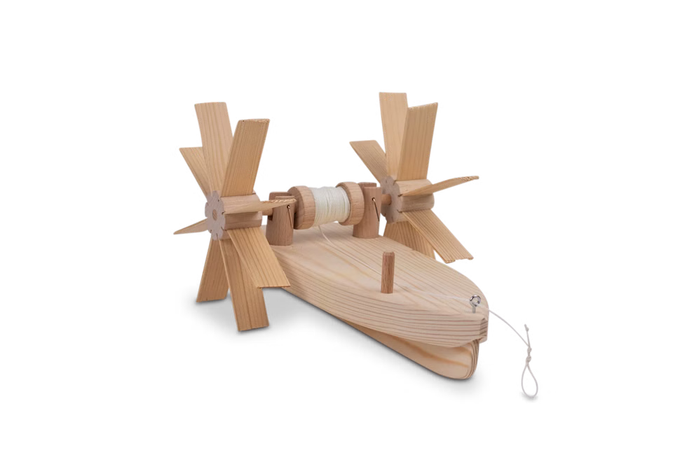 Kraul Forelle - Schiffsbausatz Bausatz_31640 Der Forelle - Schiffsbausatz Bausatz von Kraul ist ein kleines Holzbootmodell mit zwei großen Schaufelrädern auf jeder Seite die durch eine mit Schnur umwickelte Spule verbunden sind und mit einem Kurbelmechanismus versehen sind.