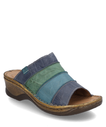 El zueco está hecho de cuero y presenta un diseño multicolor en tonos azules y verdes. Cuenta con un cierre de goma elástica cómodo y una suela robusta y texturizada en marrón que ofrece un agarre óptimo.