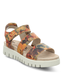 La sandale a un motif floral dans des tons chauds sur un fond beige. Elle dispose d'une fermeture velcro et d'une semelle profilée gris clair pour une meilleure adhérence.