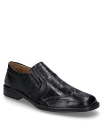 El mocasín negro está hecho de cuero brillante y tiene un cómodo cierre de goma elástica. El zapato se caracteriza por su superficie lisa y la discreta costura.