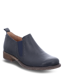 Mocassin élégant en cuir bleu marine avec un élastique confortable sur le côté. La chaussure a une semelle plate marron clair et des coutures discrètes sur les bords.
