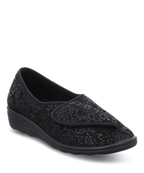 Zapatillas negras con cierre de velcro diseñadas con un elegante patrón floral en relieve. El material parece ser un tejido suave proporcionando comodidad y estilo para el uso diario.
