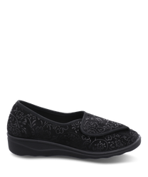 Zapatillas negras con cierre de velcro diseñadas con un elegante patrón floral en relieve. El material parece ser un tejido suave proporcionando comodidad y estilo para el uso diario.