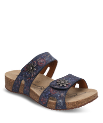 Die Sandale hat einen Klettverschluss und besteht aus einem blauen floral gemusterten Material. Besondere Merkmale sind die metallischen Blumenapplikationen auf den Riemen und die komfortable Korksohle.