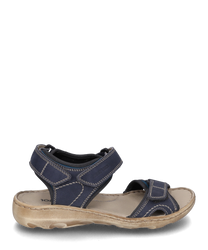 Die Sandale hat ein dunkelblaues Obermaterial mit hellen Ziernähten und einem beigen Sohlenrand. Sie verfügt über Klettverschlüsse für einfaches An- und Ausziehen und bietet einen lässigen komfortablen Look.