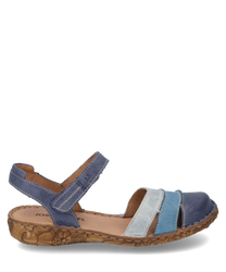 La sandale a une fermeture velcro et est en cuir multicolore dans des tons de bleu et de beige. La semelle est brun clair avec une texture discrète qui allie confort et style.