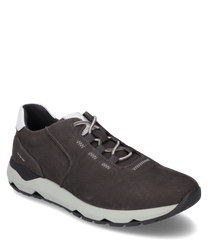 La zapatilla está hecha de cuero liso de color gris oscuro y tiene un acento blanco en el talón. Cuenta con un sistema de cordones y una suela de goma blanca robusta con detalles negros para un soporte adicional.