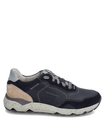 Der Sneaker ist aus glattem dunkelblauem Leder mit beigem Wildleder-Detail an der Ferse gefertigt. Er verfügt über eine markante weiße Sohle mit grauen Sprenkeln und eine Schnürung.