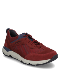 Red sneaker with lacing made of suede and textile. The shoe features a contrasting white sole and blue accents giving it a sporty look.
