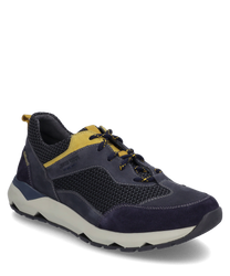 The sneaker is dark blue with yellow accents and is made from a mix of textile and suede. It features lacing and a white sole with a geometric design for added grip.