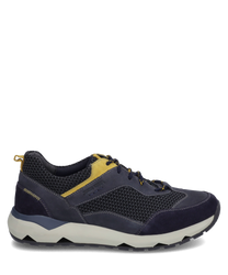 The sneaker is dark blue with yellow accents and is made from a mix of textile and suede. It features lacing and a white sole with a geometric design for added grip.