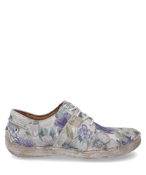 El zapato de media suela presenta un diseño floral en suaves tonos de lavanda y verde. Está hecho de un tejido texturizado con cordones lo que le da un aspecto casual y elegante.