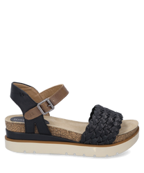 Elegante sandalo con cinturino intrecciato nero e chiusura in velcro regolabile. La suola è realizzata in materiale beige chiaro strutturato con un accento di sughero marrone.