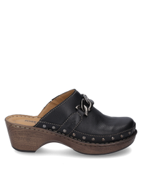 Zueco negro de cuero con elástico decorado con remaches de metal y un lazo de cadena decorativo. El zapato tiene una suela de aspecto madera marrón con un tacón medio y costuras visibles.