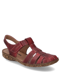 Sandalia roja de cuero con cierre de velcro punta abierta y cordones decorativos. La suela es de color marrón claro con un patrón floral lo que le da a la sandalia un aspecto especial.