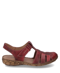 Sandalia roja de cuero con cierre de velcro punta abierta y cordones decorativos. La suela es de color marrón claro con un patrón floral lo que le da a la sandalia un aspecto especial.