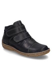 Botín negro de cuero con cierre de velcro y suela marrón claro. El zapato presenta costuras blancas marcadas y una suela exterior robusta y antideslizante.