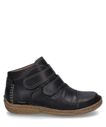 Botín negro de cuero con cierre de velcro y suela marrón claro. El zapato presenta costuras blancas marcadas y una suela exterior robusta y antideslizante.