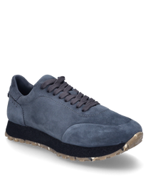 La sneaker è realizzata in camoscio blu scuro e presenta una chiusura con lacci. La suola è nera con un profilo beige che offre una presa aggiuntiva.