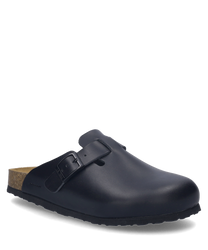 El zueco negro de material liso cuenta con un cierre de hebilla ajustable. La suela es de color marrón claro lo que ofrece un contraste elegante.