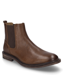 De enkellaars in de kleur cognac is gemaakt van hoogwaardig leer en heeft een elastische rubberen band voor gemakkelijk aan- en uittrekken. De schoen heeft een eenvoudige en elegante uitstraling met een platte zool.