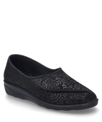 La zapatilla de casa es negra y está equipada con un cierre de velcro. Está hecha de un material estampado con diseños florales que le dan al zapato una apariencia elegante.