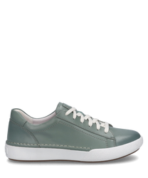 Une sneaker couleur sauge avec lacets en cuir lisse. La chaussure a une semelle blanche et texturée avec des coutures discrètes.