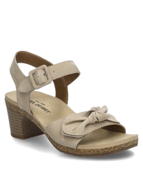 Sandale beige avec fermeture velcro et nœud décoratif. La chaussure a un talon bloc de hauteur moyenne avec un aspect liège et est fabriquée en matériau lisse.