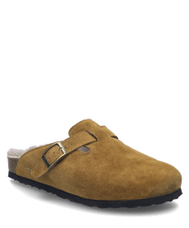 Le sabot de couleur camel est en daim doux et est doté d'une boucle comme fermeture. La doublure en fourrure offre un confort et une chaleur supplémentaires.