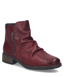La bota de cuero color burdeos cuenta con una cremallera lateral y pliegues decorativos en el lado exterior. El zapato tiene una suela plana con un ligero tacón ideal para una apariencia elegante y cómoda.