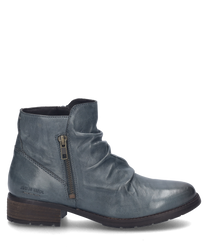 La bota azul destaca por su suave cuero y un elegante cierre de cremallera en el lateral. El zapato tiene una superficie texturizada y una suela robusta de color marrón oscuro ideal para los días de otoño con estilo.