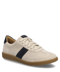 La zapatilla está en beige y negro con un cierre de cordones y un borde de suela texturizado en marrón claro. La parte superior parece estar hecha de un tejido suave y un detalle negro adorna el costado.