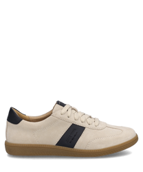 La zapatilla está en beige y negro con un cierre de cordones y un borde de suela texturizado en marrón claro. La parte superior parece estar hecha de un tejido suave y un detalle negro adorna el costado.