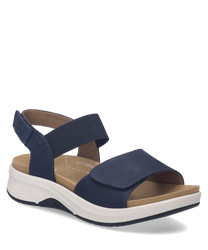 These sandals feature a navy blue leather-like material with Velcro closure and a cushioned tan insole offering comfort and support. The sole is white providing a stylish contrast.
