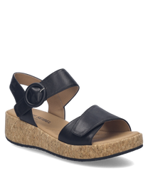 Black sandals featuring a Velcro closure with a circular buckle. The sandals have a cork wedge sole providing comfortable elevation.