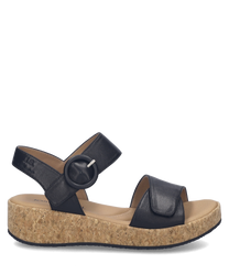 Black sandals featuring a Velcro closure with a circular buckle. The sandals have a cork wedge sole providing comfortable elevation.