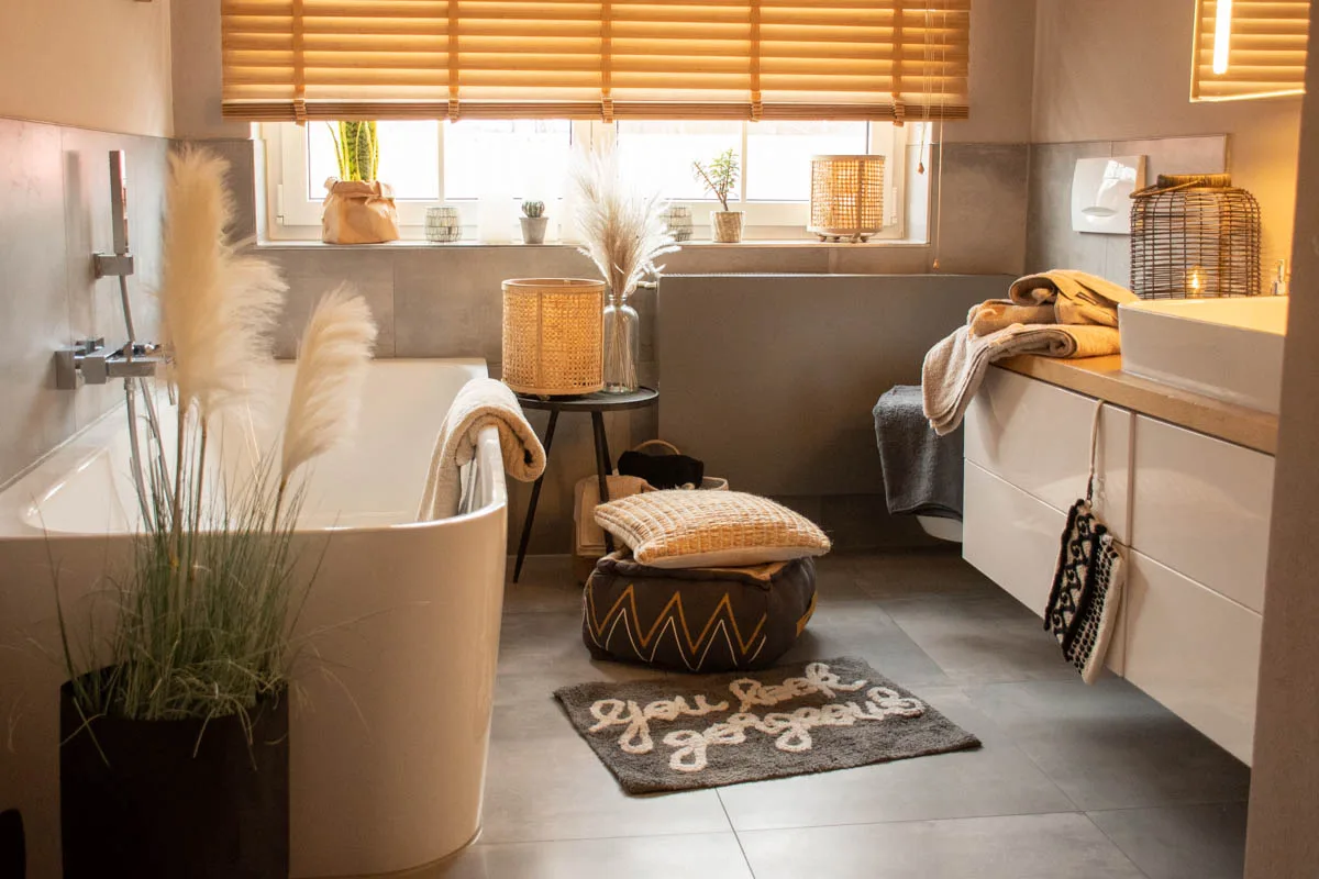 Badezimmer mit Wohnaccessoires: Körbe, Laterne, Sitzpouf und Kissen