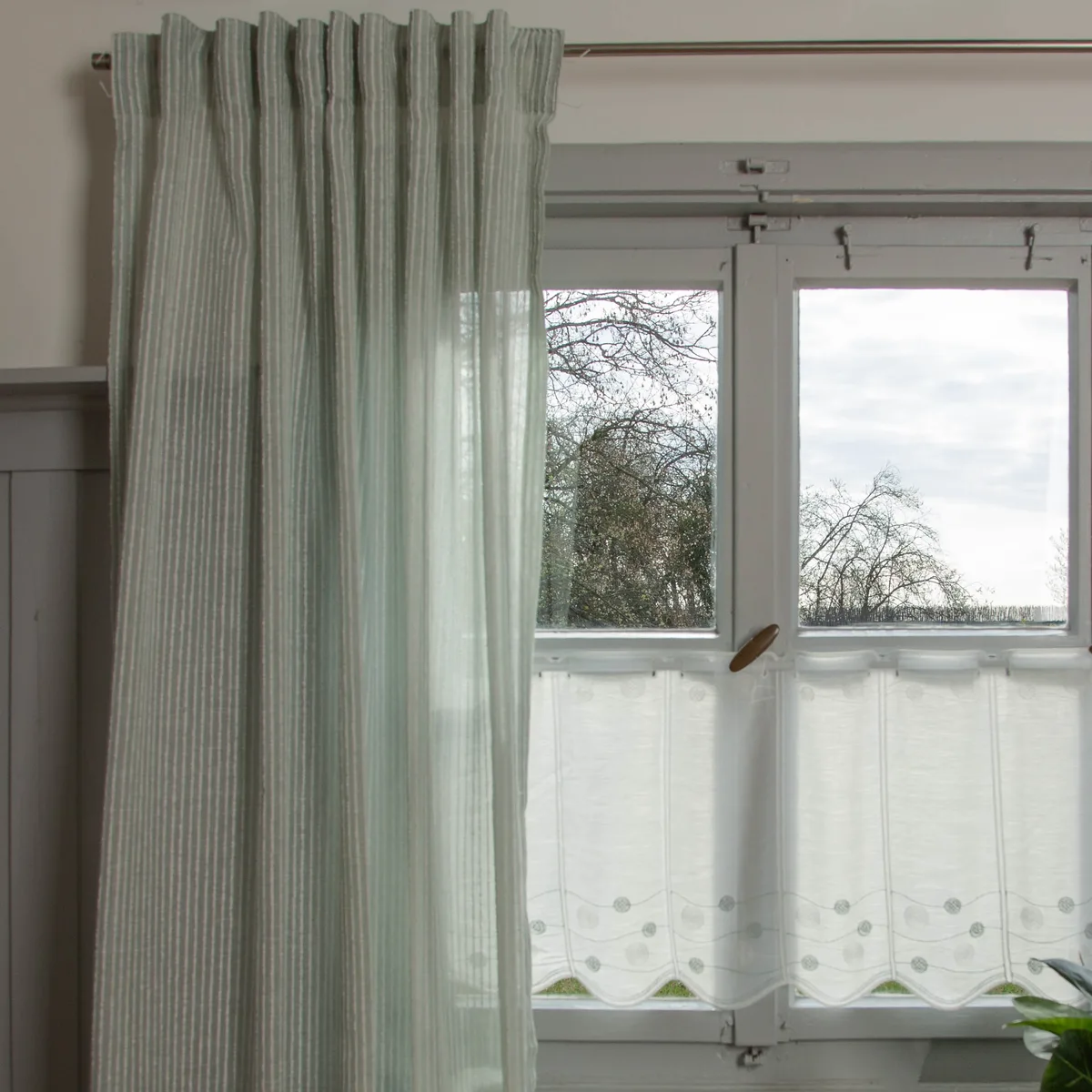 Mintgr&uuml;ne Fertiggardine mit Scheibengardine und Kissen am Fenster