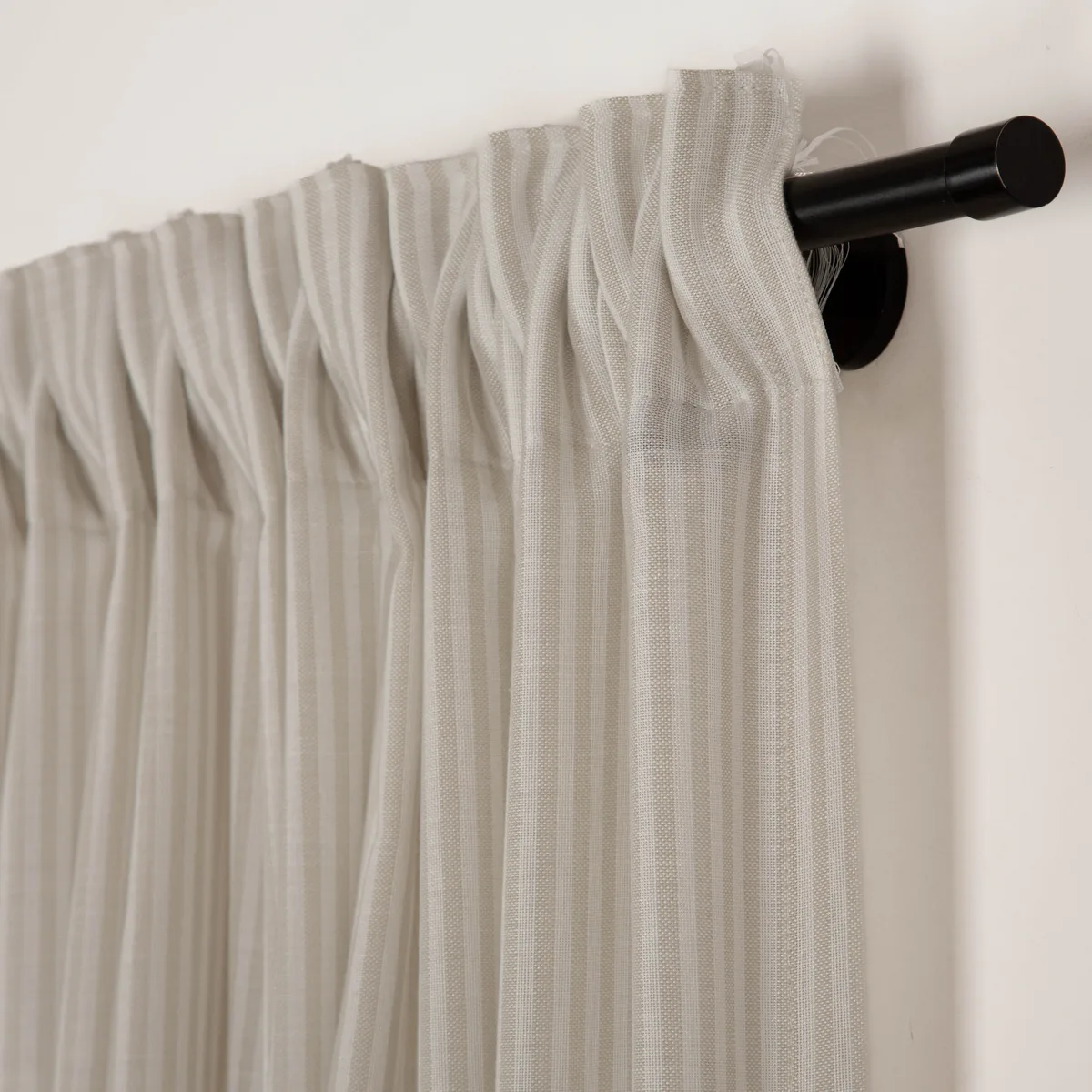 Raumhoher Store in Creme mit Faltenband an schwarzer Gardinenstange – Detailansicht