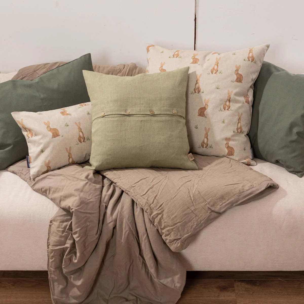 Kissen 40x60 cm mit Hasenmotiv kombiniert mit grünen Leinenkissen auf heller Couch