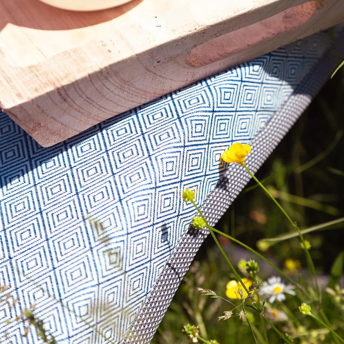 Blaue Sitzauflage mit Rautenmuster auf einer Gartenliege – Detail