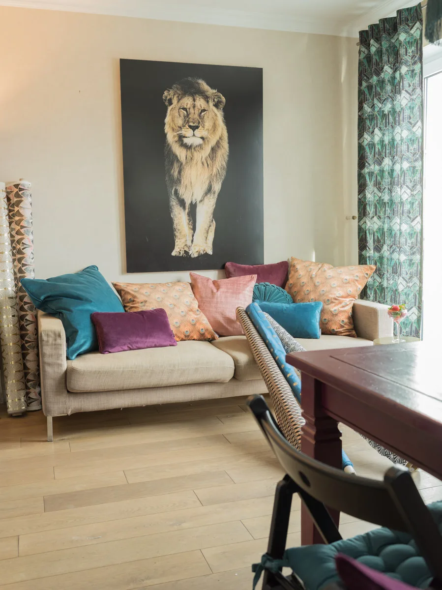 Sofa mit Samtkissen vor Vorhang aus Retro-Dekostoff mit Art-déco-Muster in Grün