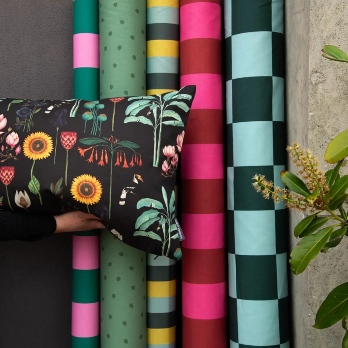 Dekostoffe als Rollen in kräftigen Farben mit floralem Kissen