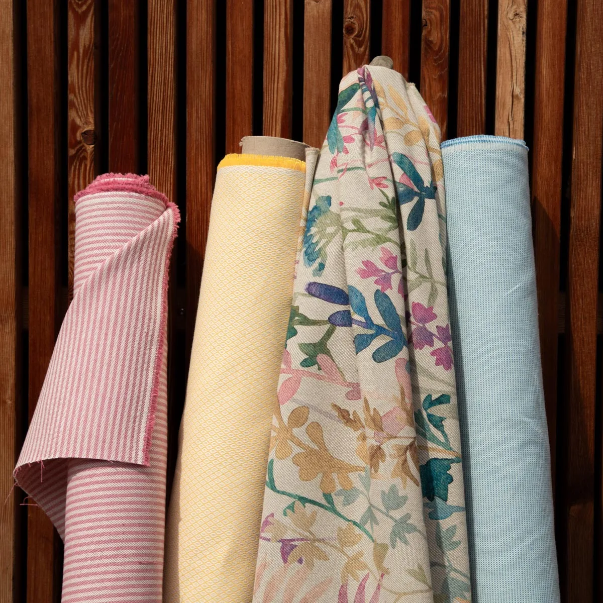 Dekostoff-Rollen in Gelb, Rosa und Hellblau mit Streifen und Blüten